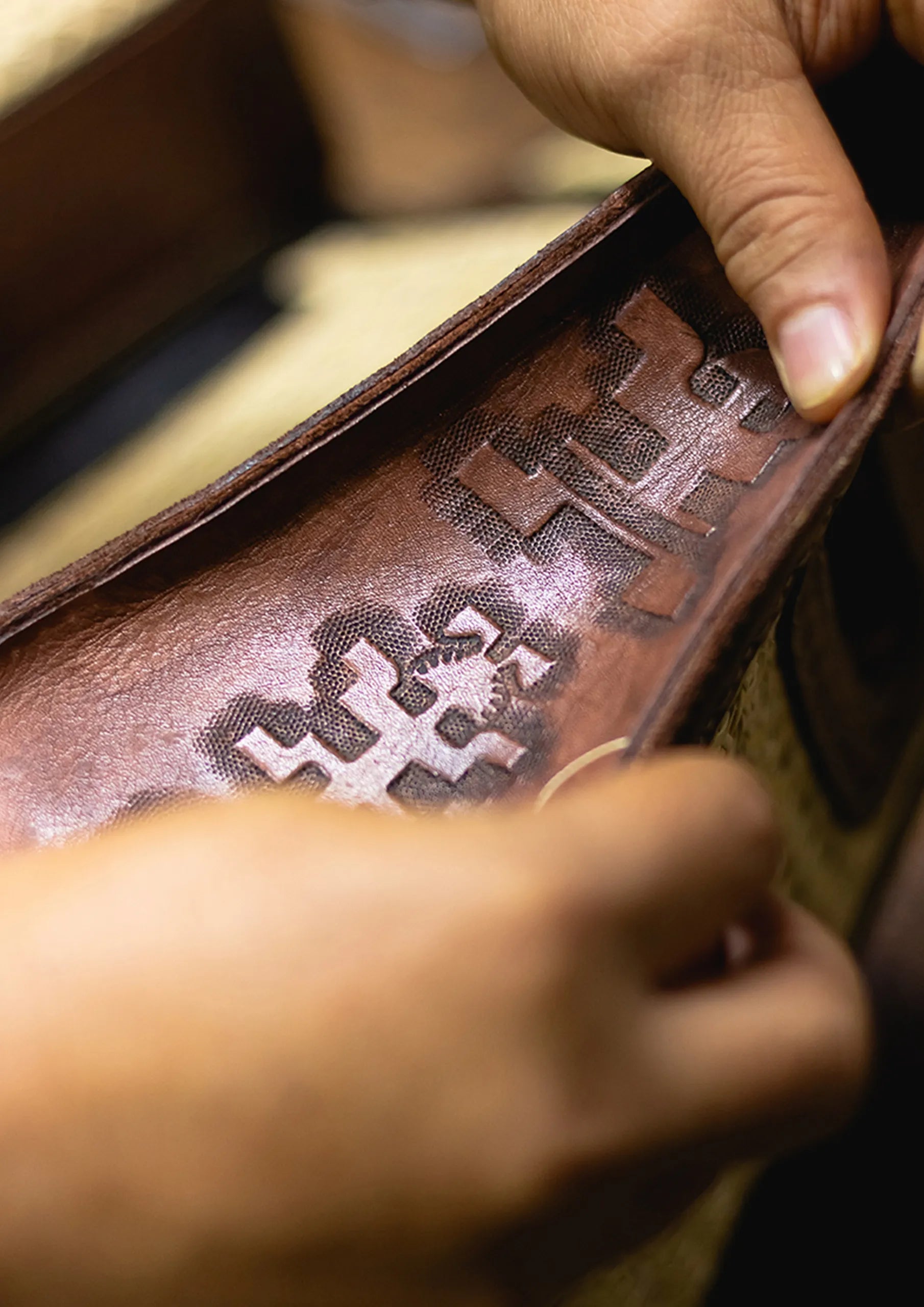 Primer plano de una mujer tejiendo una bolsa de hojas de palma de iraca. Se aprecia un dibujo lineal precolombino en uno de sus laterales.
